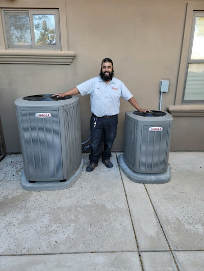 A man stands beside two air conditioning units